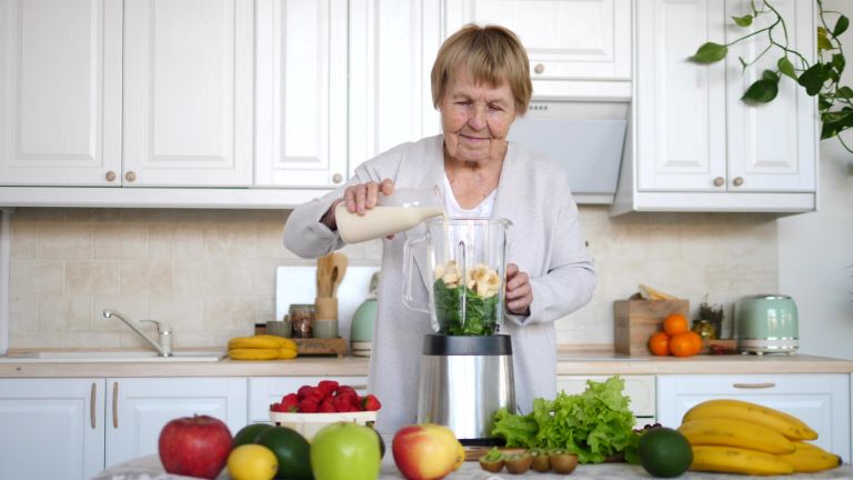 An older woman making a smoothie